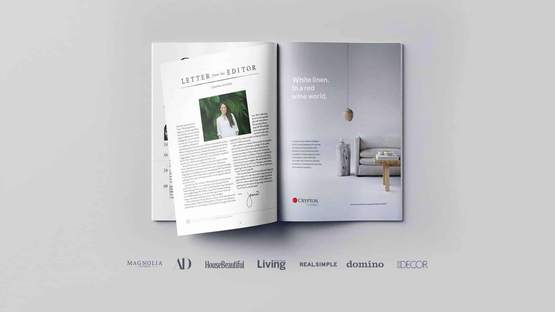 Two-page magazine spread: left page shows an article by an editor with a portrait; right page features a minimalist ad with a white sofa and hanging light, captioned "White linen. In a red wine world." Logos of various publications are below.