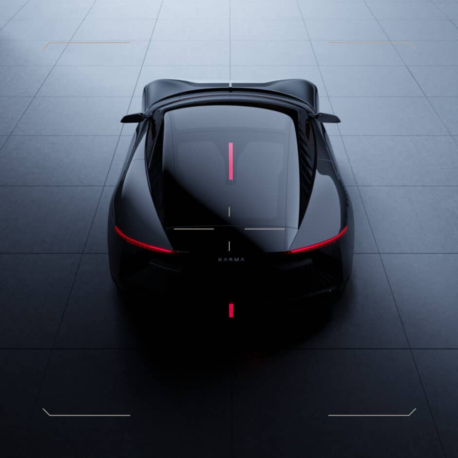 Sleek black sports car viewed from above on a gray tiled floor. The car has a glossy finish with a red accent line and glowing red rear lights.