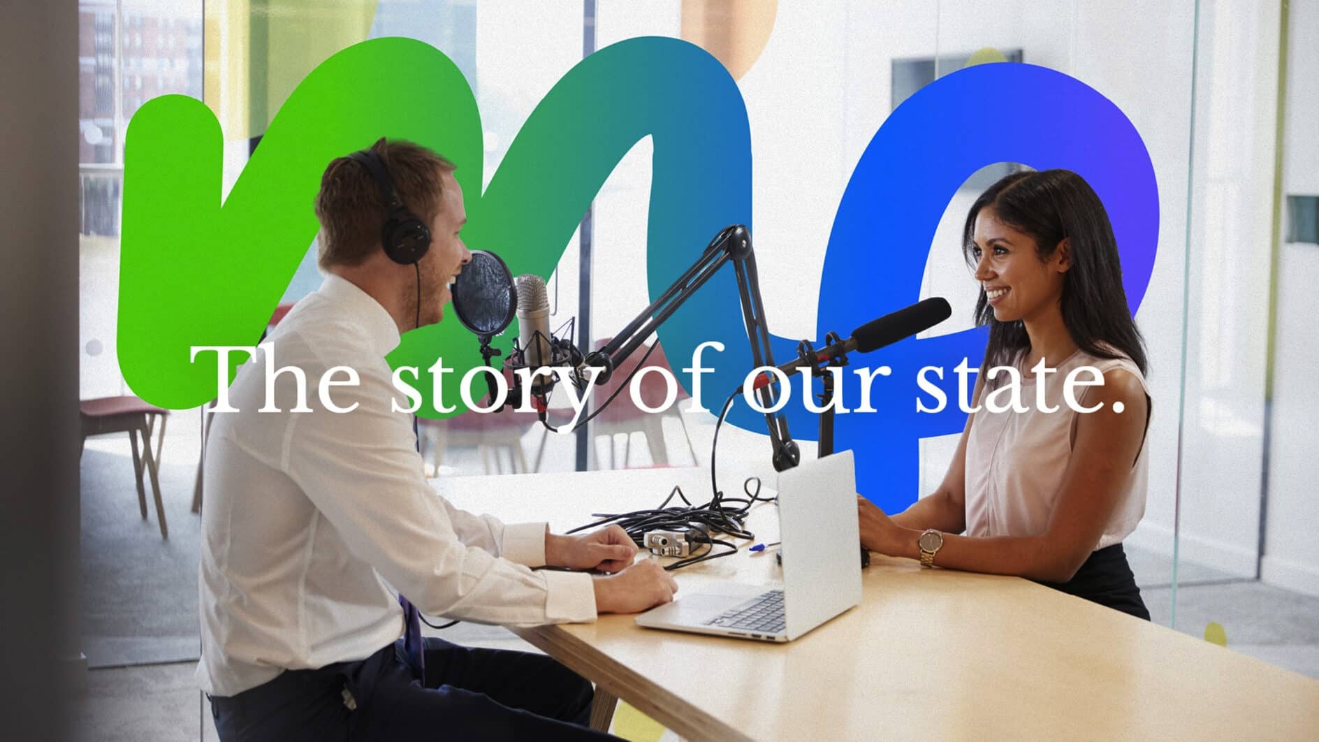 A man and woman record a podcast in a modern studio with bright colors. Text reads "The story of our state," suggesting a relaxed, informative discussion.