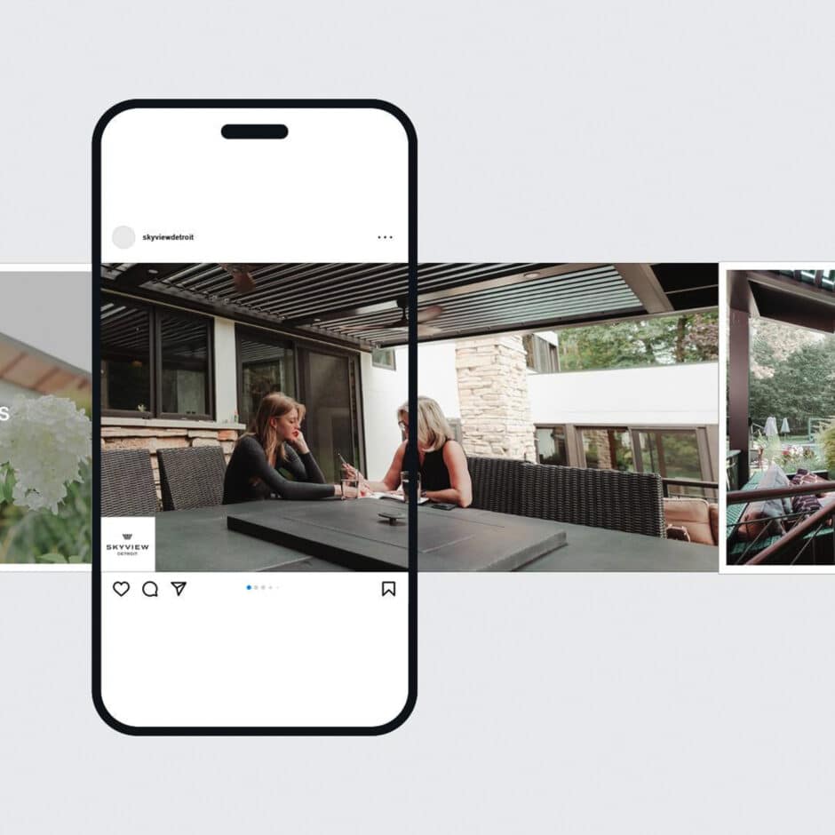 A smartphone displays a photo of two women seated at a patio table, engaged in conversation. The setting features modern outdoor furniture and a scenic backdrop.