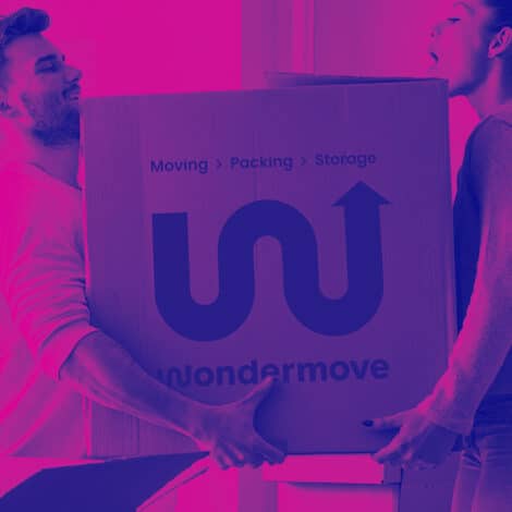 Two people lift a large cardboard box labeled "wondermove" with "Moving > Packing > Storage." The image has a purple-pink gradient, conveying teamwork.