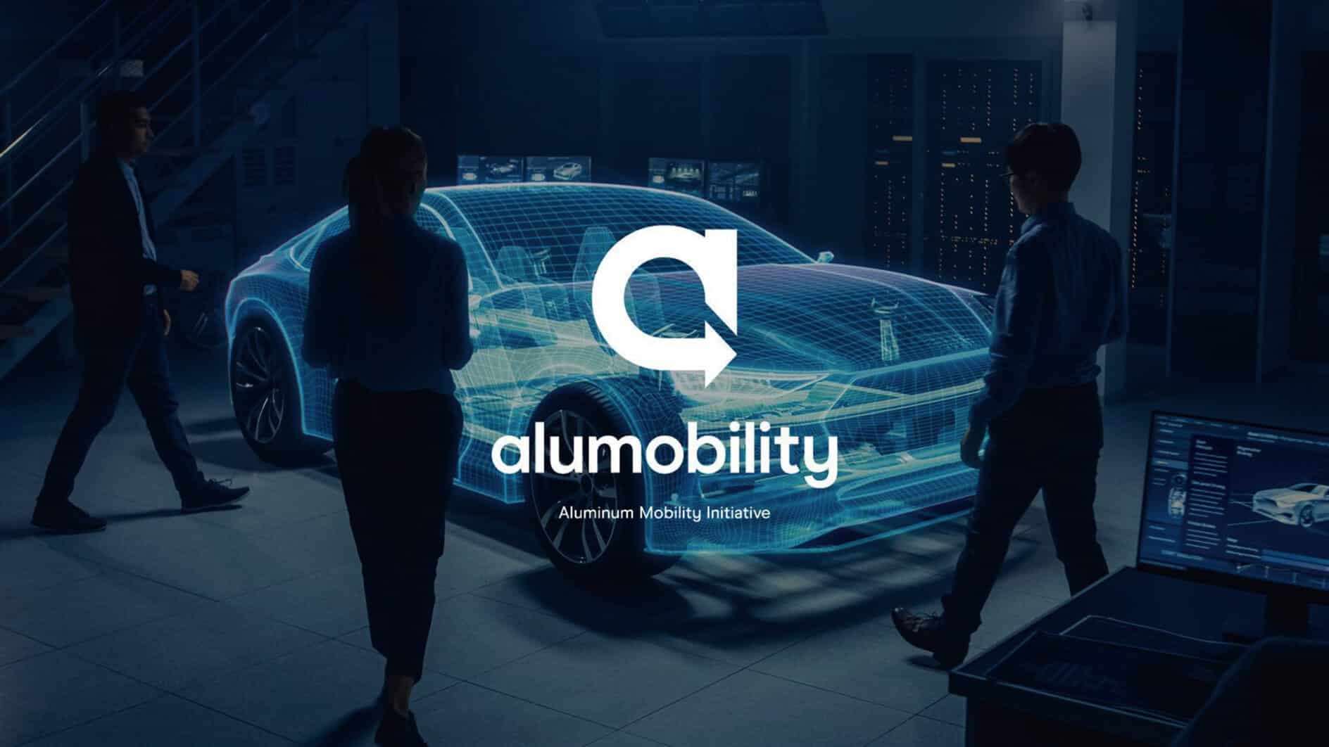 Three people stand around a holographic car model in a futuristic lab setting, conveying innovation. The "Alumobility" logo is superimposed.