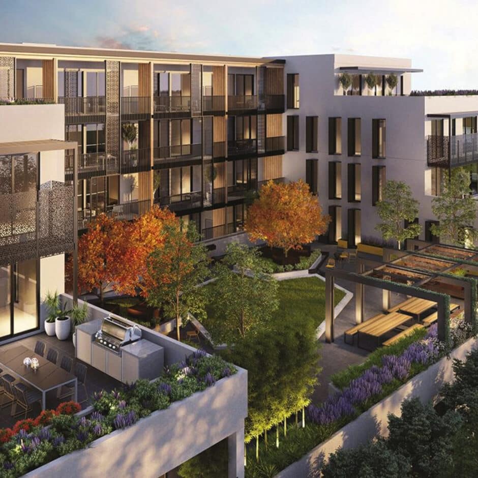 Modern apartment building with a lush rooftop garden featuring autumn-colored trees, seating areas, and a terrace with dining table and barbecue grill.