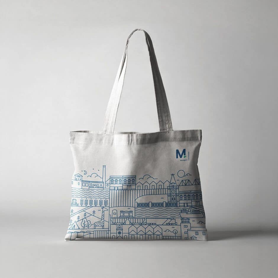 White tote bag with blue line art of a city skyline, including buildings and a clock tower. Minimalistic and modern design, creating a calm, urban vibe.
