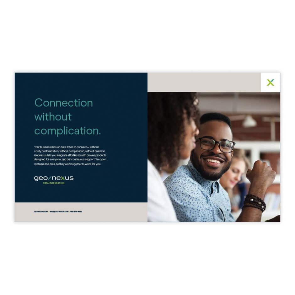 A smiling man in glasses sits at a table with colleagues, exuding positivity. The text on the left reads “Connection without complication" by GeoNexus.