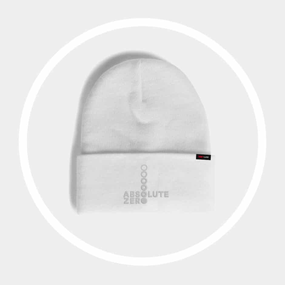 A minimalist white beanie with "ABSOLUTE ZERO" in faint gray text, features a small black and red label on the folded edge. The tone is sleek and modern.