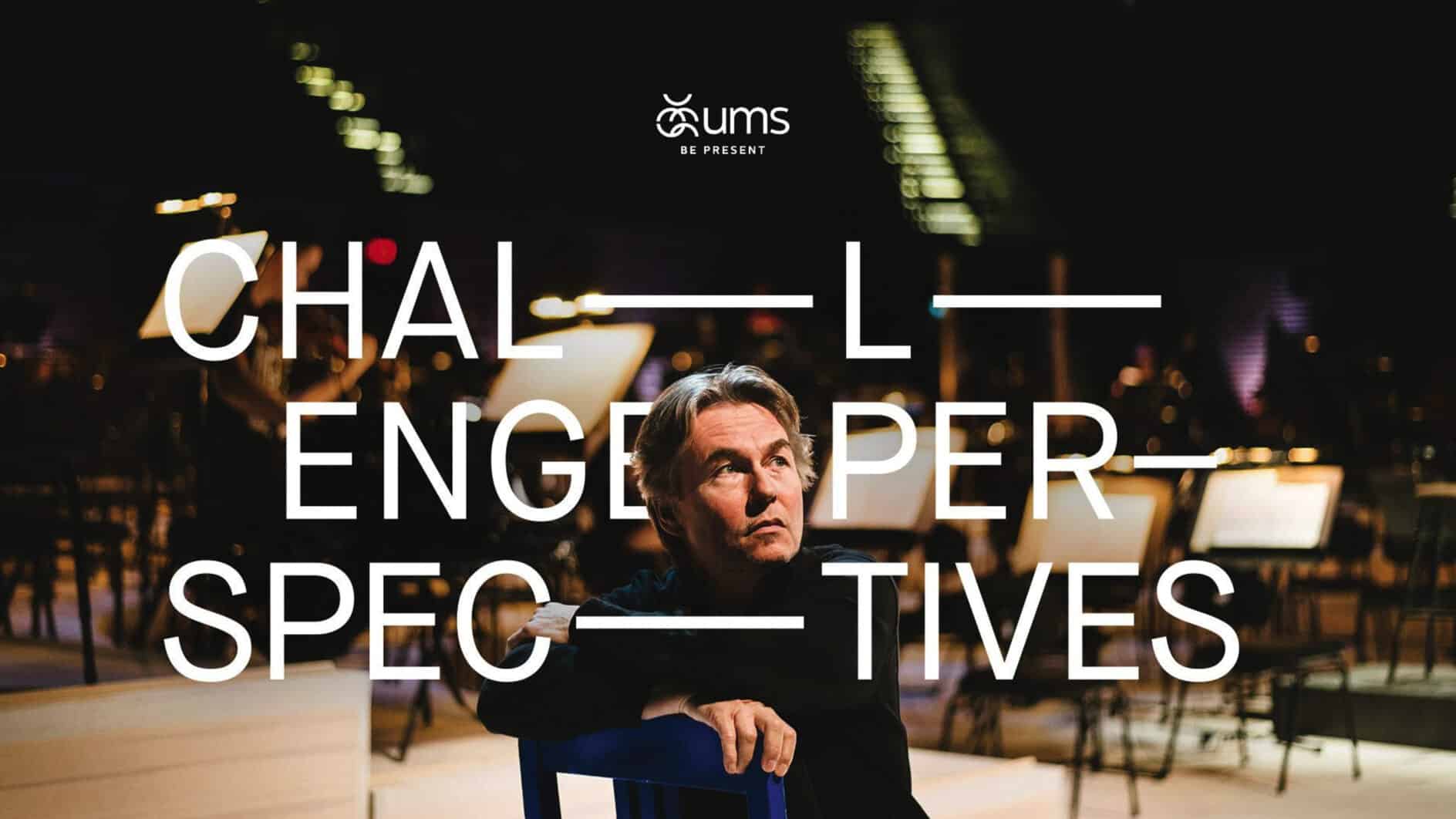 A contemplative man sits on a blue chair in a dimly lit theater, surrounded by blurred music stands. Overlaid text reads "Challenge Perspectives."