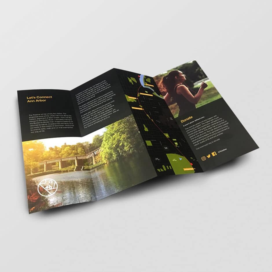 Tri-fold brochure with outdoor themes. Left panel shows a scenic bridge over water in Ann Arbor. Right panel features a person running, suggesting activity.