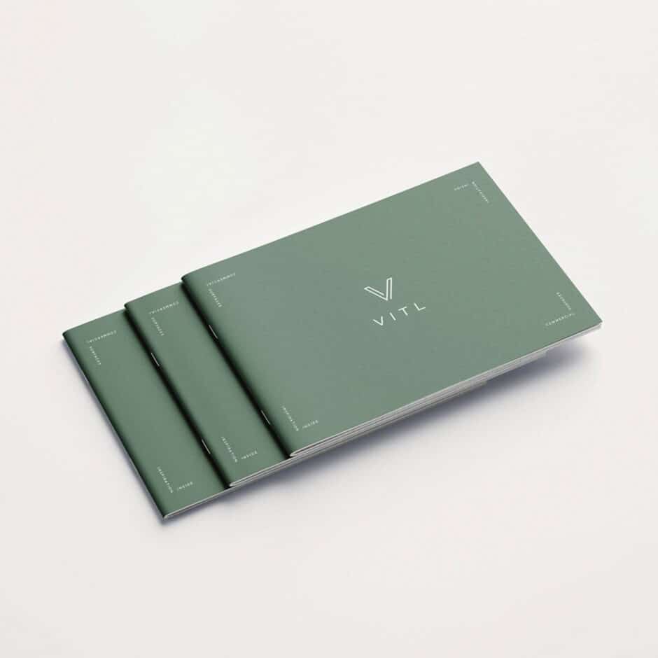 Three green brochures with "VITL" printed on the cover are stacked. The minimalist design is clean, modern, and conveys a sense of professionalism.