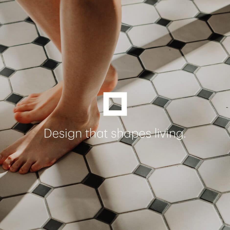 Bare feet stand on a hexagonal patterned tile floor with black accents. The text reads "Design that shapes living," conveying a modern, stylish vibe.