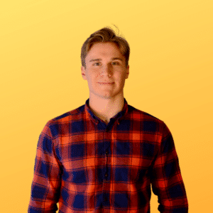 A young man in a red and blue plaid shirt smiles against a vibrant yellow background. The scene conveys a warm and friendly tone.