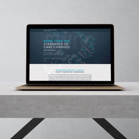 A laptop on a wooden desk displays a website with dark blue background and text: "More than 100 standards of care changed." Tone is professional and hopeful.