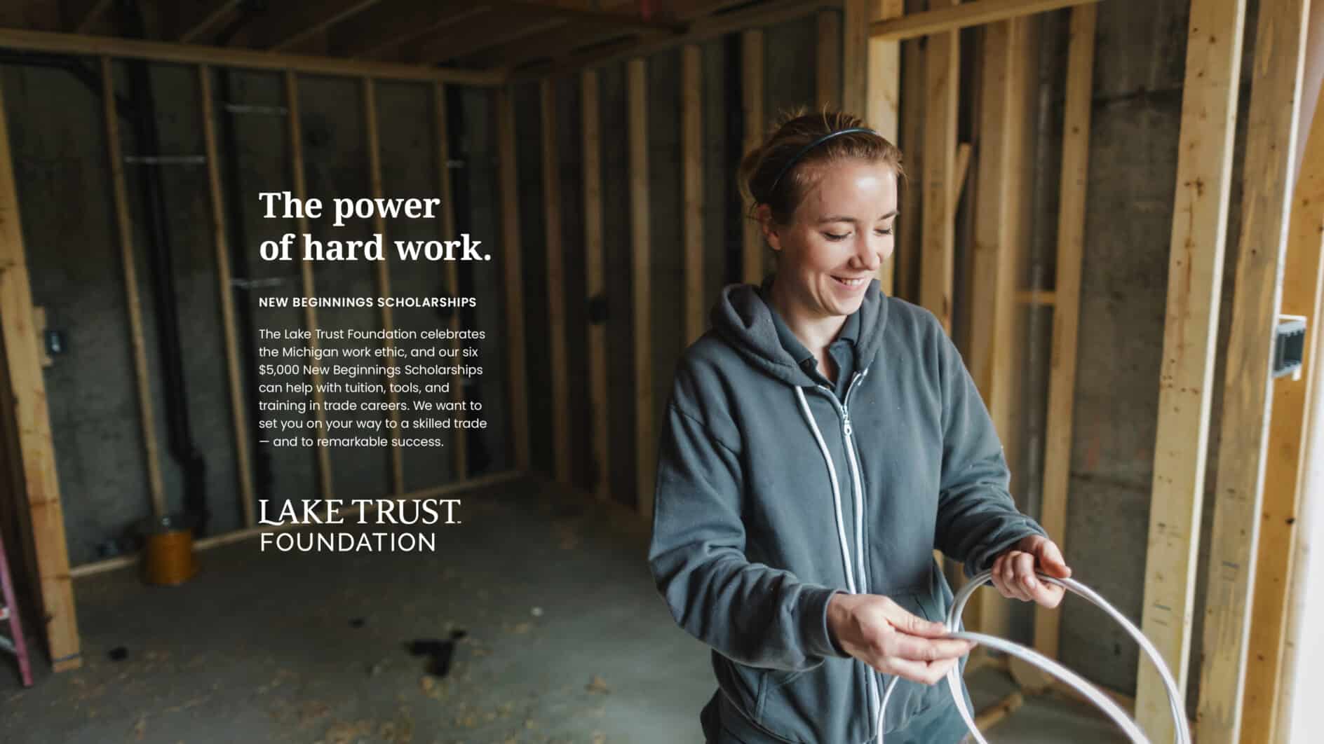 A woman in a construction setting smiles as she holds wiring in a partially built interior. Text reads "The power of hard work." Promotes scholarships.
