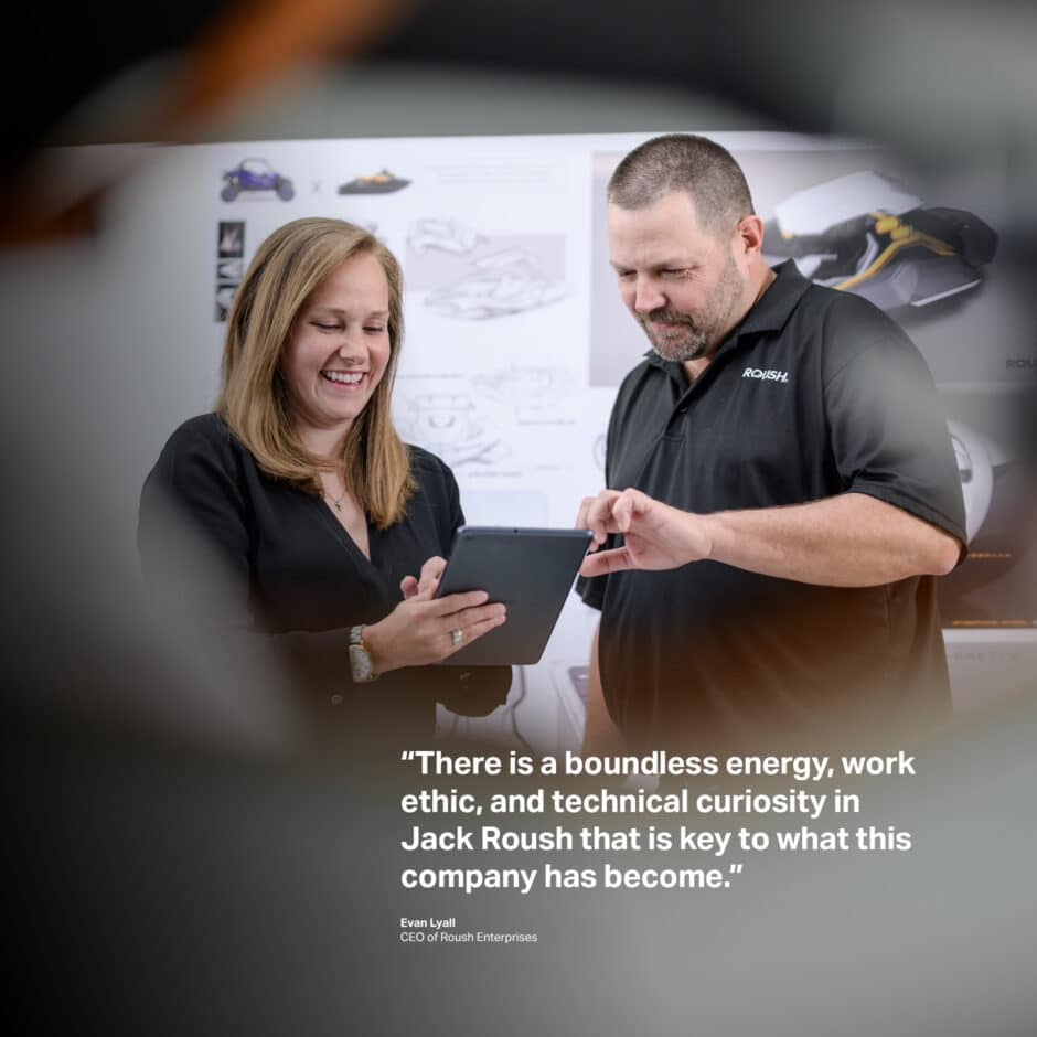 A man and woman, both smiling, collaborate using a tablet in an office setting. In the background is an automotive design board. A quote overlays the image expressing admiration for Jack Roush's influence on the company.