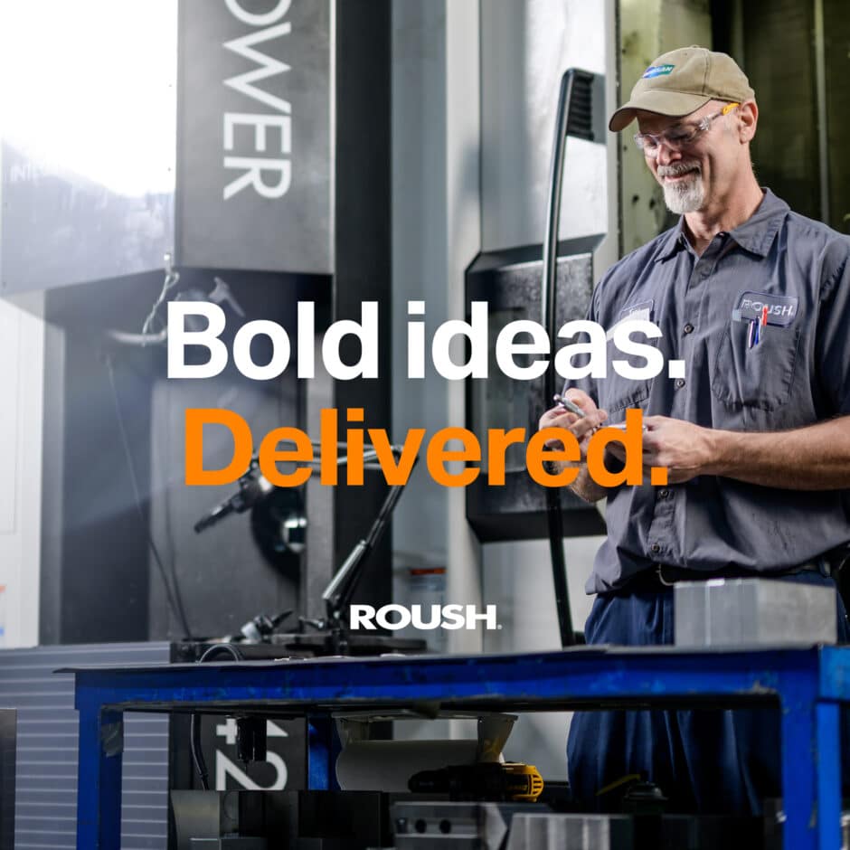 Man in a workshop wearing safety glasses and a cap, working with tools. Text reads "Bold ideas. Delivered." The atmosphere is focused and industrious.