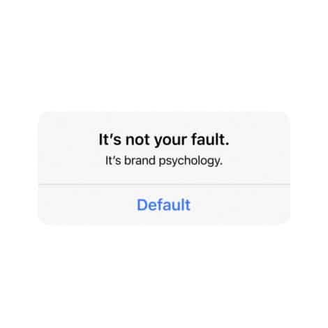 White background with centered black text: "It's not your fault. It's brand psychology." Below, blue text reads "Default," suggesting default choices.