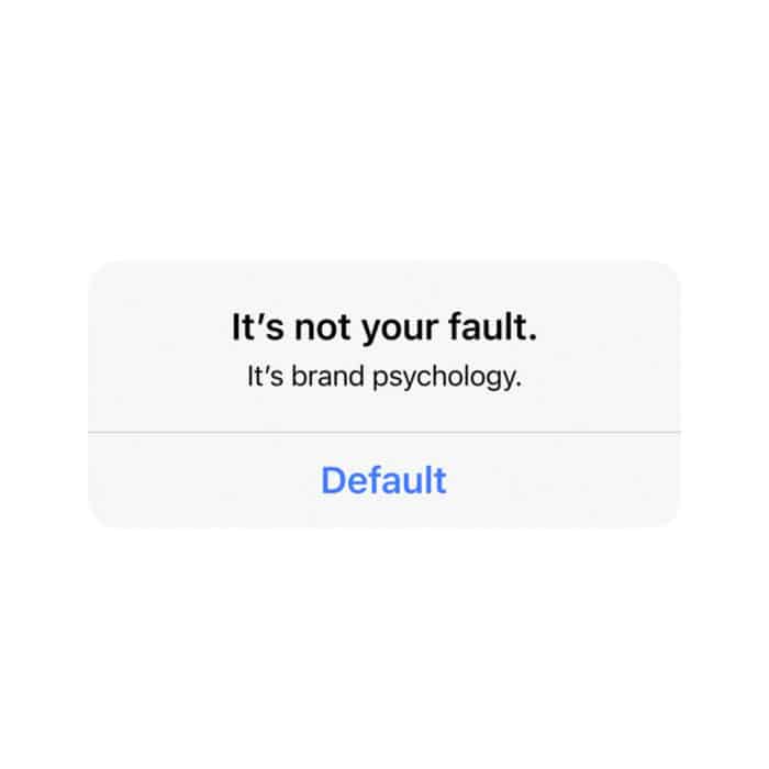 White background with centered black text: "It's not your fault. It's brand psychology." Below, blue text reads "Default," suggesting default choices.