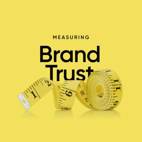 Yellow measuring tape rolled and curved on a bright yellow background. Black text reads "Measuring Brand Trust," conveying evaluation and reliability.