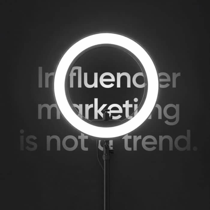 A bright ring light on a stand illuminates the words "Influencer marketing is not a trend" on a dark background, conveying a bold, modern message.