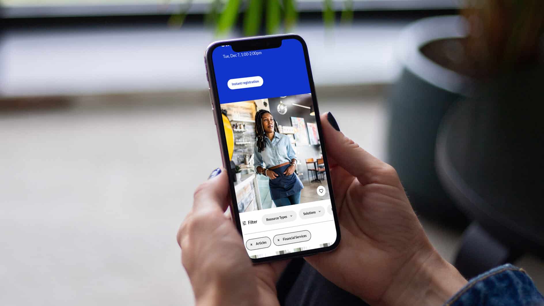 A person holds a smartphone showing a woman in a casual denim outfit on screen. The phone display includes icons for filters and settings.