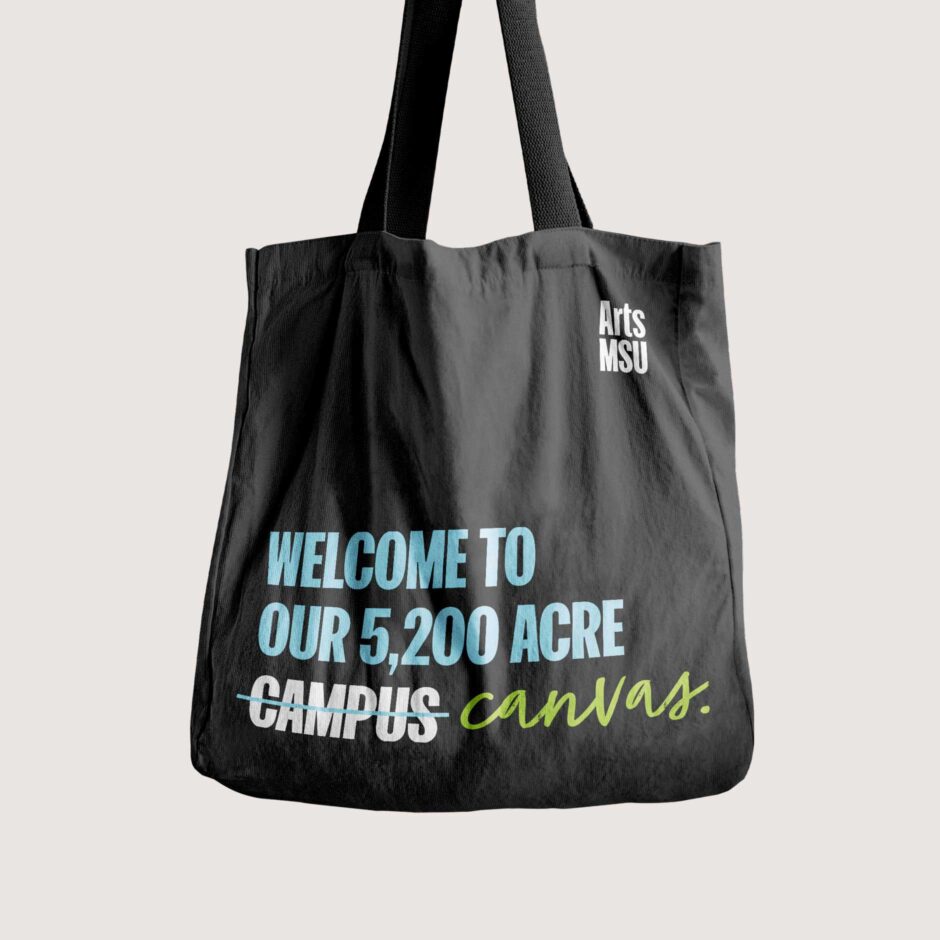 Black tote bag with the text "Welcome to our 5,200 acre campus" with "campus" replaced by "canvas," in a script font. The Arts MSU logo is in the top right corner of the tote bag.