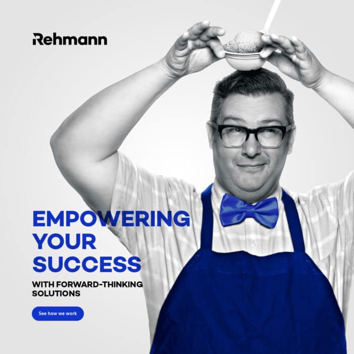 A cheerful man in glasses, wearing a blue apron and bow tie, holds a bowl with a small sphere above his head. Text reads "Empowering Your Success."